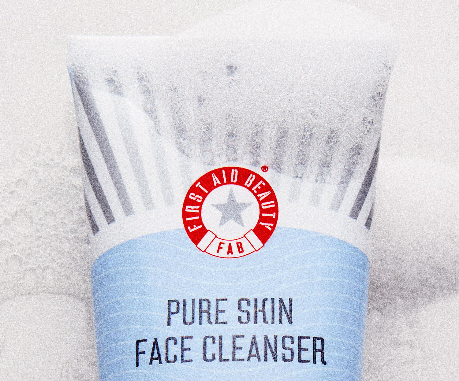 Tube of First Aid Beauty Pure Skin Face Cleanser on a textured white background